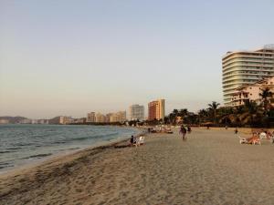 a beach with people and the ocean and buildings at Encanto Apartahotel in Santa Marta