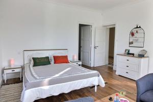 - une chambre blanche avec un grand lit et 2 oreillers rouges dans l'établissement Nombril de venus, à Tonquédec