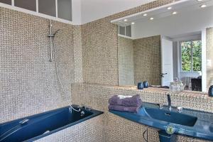 La salle de bains est pourvue d'une baignoire bleue et d'un miroir. dans l'établissement Nombril de venus, à Tonquédec
