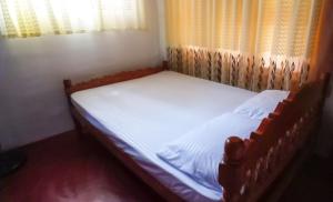 uma pequena cama num quarto com uma janela em Sinharaja Pitadeniya Hut em Deniyaya