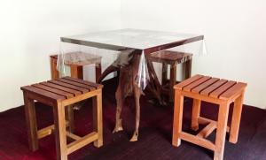 uma mesa e dois bancos com tampo de vidro em Sinharaja Pitadeniya Hut em Deniyaya