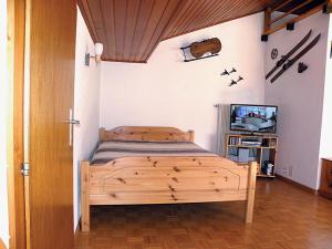 a bedroom with a wooden bed and a television at La Montagnette, VERCORIN in Vercorin