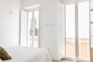 a bedroom with white walls and large windows at Villalobos Suites by Luxury Suites Cadíz in Cádiz