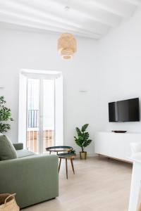 a living room with a couch and a tv at Villalobos Suites by Luxury Suites Cadíz in Cádiz