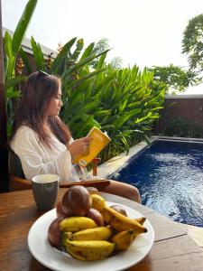 una mujer sentada en una mesa con un plato de plátanos en Bhumi Lovina Residence & Villa, en Singaraja