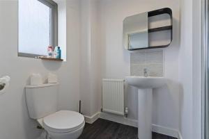 a white bathroom with a toilet and a sink at Exquisite 7 Bedroom 5.5 Bathroom House - Over 1900 sqft - Close to City Centre with Free Parking, Fast W-Fi and SmartTVs by Yoko Property in Northampton