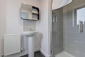 ein Bad mit einem Waschbecken und einer Dusche mit einem Spiegel in der Unterkunft Exquisite 7 Bedroom 5.5 Bathroom House - Over 1900 sqft - Close to City Centre with Free Parking, Fast W-Fi and SmartTVs by Yoko Property in Northampton