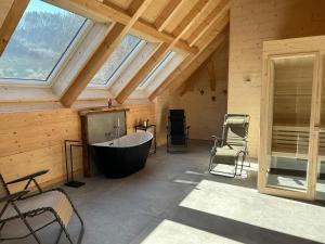uma casa de banho com uma grande banheira num quarto com janelas em Ferienwohnung im Loft-Style mit Sauna im historischen Schwarzwaldhof em Simonswald