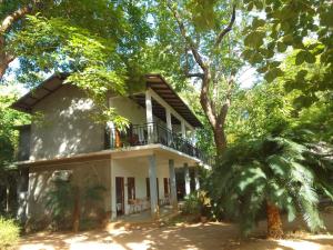 a white house with a balcony and trees at Sisila Guest House in Polonnaruwa