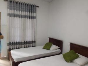 a bedroom with two beds and a curtain at Sisila Guest House in Polonnaruwa