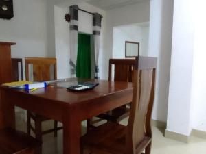 a wooden dining room table with chairs and a green curtain at Sisila Guest House in Polonnaruwa