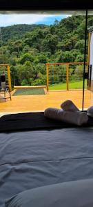łóżko w pokoju z widokiem na taras w obiekcie Domo da Montanha w mieście Monte Verde