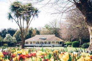 a house in a park with flowers in front of it at The Kings Harbour Hotel in Christchurch