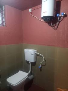 een badkamer met een toilet en een camera aan de muur bij ITIKA HOME STAY in Shānti Niketan