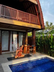 una mujer sentada junto a una piscina al lado de una casa en Bhumi Lovina Residence & Villa, en Singaraja