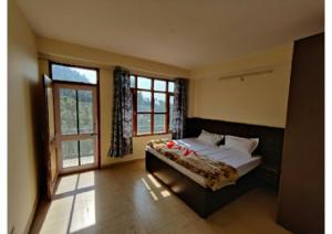 ein Schlafzimmer mit einem Bett und einem großen Fenster in der Unterkunft Hotel Gopi Dham Ashram Haridwar Near Vrindavan in Haridwar