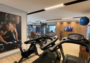 a gym with two cardio machines and a painting of a woman at Fiesta Bahia Hotel in Salvador