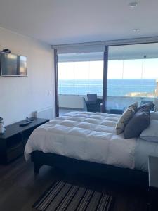 1 dormitorio con 1 cama grande y vistas al océano en Departamentos Mednav Montemar & Spa en Concón