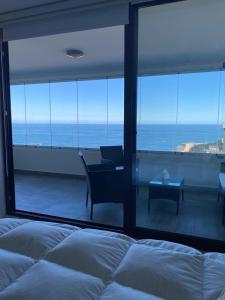 una camera da letto con un letto e vista sull'oceano di Departamentos Mednav Montemar & Spa a Concón Altre 22 foto