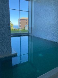 una piscina en un edificio con reflejo en el agua en Departamentos Mednav Montemar & Spa en Concón