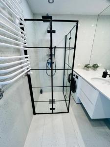 a glass shower door in a bathroom with a sink at Apartment Targowa L10 in Lublin