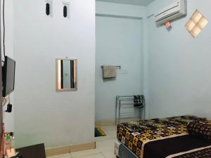 een slaapkamer met een bed en een spiegel bij Wisma Dhana Syariah in Praya