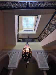 una lámpara de araña colgada del techo con una ventana en Riad Paolo Piscine Palmeraie, en Marrakech