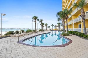 einen Pool am Strand mit Palmen und einem Gebäude in der Unterkunft Calypso Beach Resort Towers in Panama City Beach