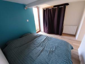 ein Schlafzimmer mit einem Bett mit blauer Wand und einem Fenster in der Unterkunft Au Nid Douillet in Saint-Jans-Cappel