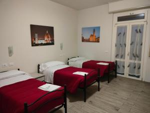 フィレンツェにあるイル グリロ ディ フィレンツェ B&Bの赤いシーツが備わる部屋のベッド3台