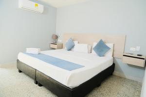 a bedroom with a large white bed with blue pillows at Casa Franco Hotel in Cartagena de Indias