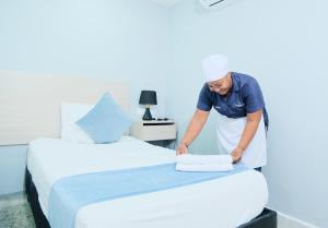 un hombre poniendo toallas en una cama en una habitación en Casa Franco Hotel en Cartagena de Indias