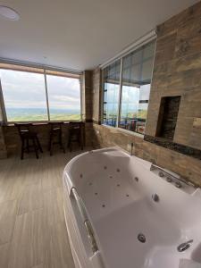 ein großes Bad mit einer Badewanne und einem großen Fenster in der Unterkunft Villa Jair Hotel in Filandia
