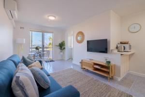 a living room with a blue couch and a tv at Stunning Apartment In South Perth in Perth