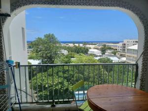 balcón con mesa y vistas al océano en Appartement spacieux en Sainte-Clotilde