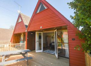 een rode schuur met een veranda en een bank op een dek bij Chalet Twentynine in Deal