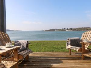 2 sillas y una mesa en una terraza con agua en White Sails en Y Felinheli