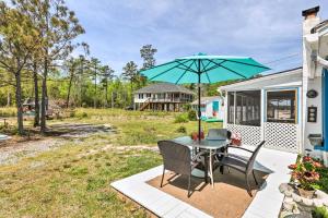 un patio con mesa, sillas y sombrilla en Oceanfront White Stone Cottage with Private Beach!, en White Stone