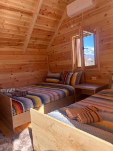two beds in a log cabin with a window at Cozy bungallows in Podgorica