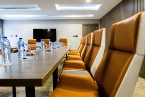 BON Hotel Nest Garki II Abuja في أبوجا: قاعة المؤتمرات مع طاولة وكراسي طويلة