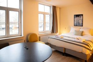 um quarto com uma cama, uma mesa e janelas em Smartflats - L'Orangerie I Maastricht em Maastricht