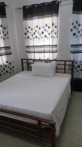 a bedroom with a bed with white sheets and curtains at Bamboo House BnB in Bondeni