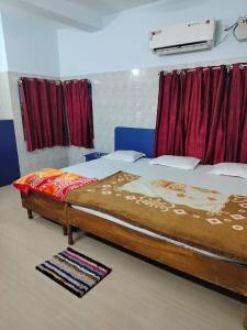 a large bed in a room with red curtains at Hotel basanti in Puri