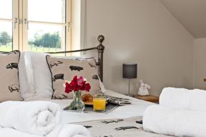 een kamer met een bed met een vaas met bloemen en sinaasappelsap bij Piggery Cottage in Llanasa