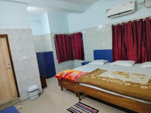 a bedroom with a large bed with red curtains at Hotel basanti in Puri