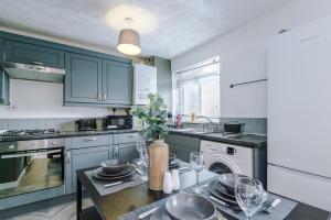 una cocina con armarios azules y una mesa con copas de vino en Delighful Family House in Stalybridge Sleeps 9 with WiFi by PureStay, en Stalybridge