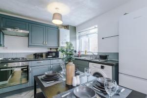 una cucina con armadi blu e un tavolo con bicchieri da vino di Delighful Family House in Stalybridge Sleeps 9 with WiFi by PureStay a Stalybridge