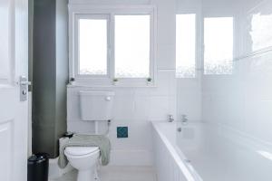 baño blanco con bañera y aseo en Delighful Family House in Stalybridge Sleeps 9 with WiFi by PureStay, en Stalybridge