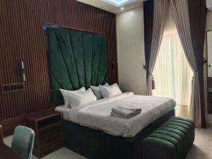 a bedroom with a large bed with a green headboard at Passready Hotel and Suites Nnewi in Nnewi