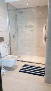 a white bathroom with a shower and a toilet at New Cozy Sea View Apartment in Manama